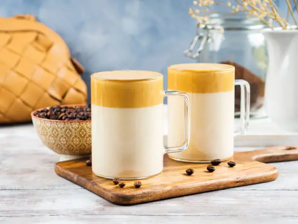 Whipped dalgona coffee drink in glass mug. Cozy breakfast with trendy beverage