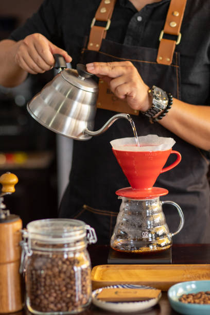 istock Barista brewing coffee in pour over in red V60 cup 1324853066