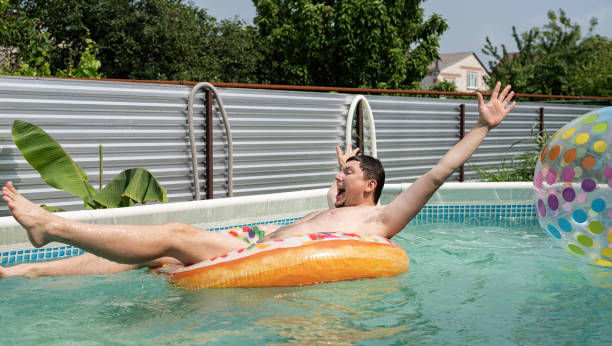 giovane che si diverte in piscina su tubo gonfiabile - swimming tube inflatable circle foto e immagini stock