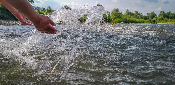 istock Male hands raise water from a mountain river 1324853503