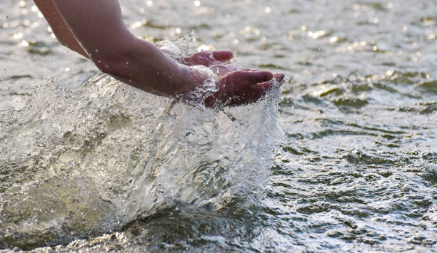 istock Male hands raise water from a mountain river 1324853523