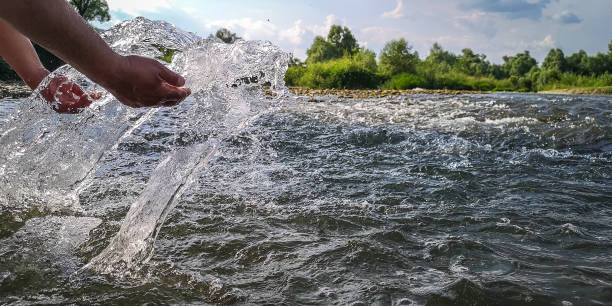 istock Male hands raise water from a mountain river 1324853530
