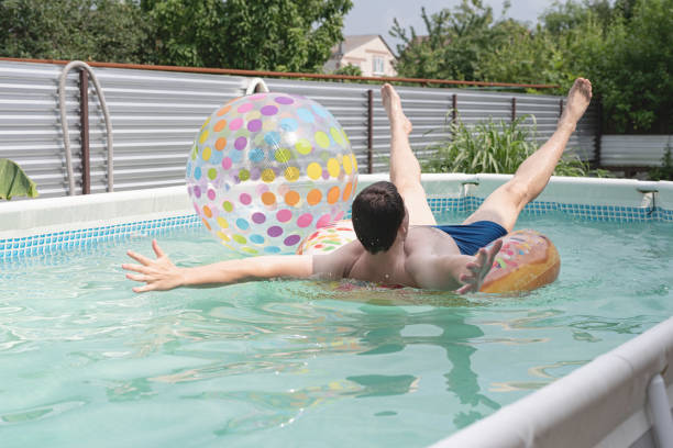 giovane che si diverte in piscina su tubo gonfiabile - swimming tube inflatable circle foto e immagini stock