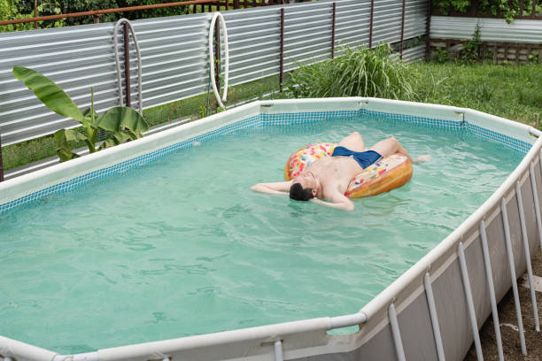 giovane prendere il sole su tubo gonfiabile nuoto in piscina - swimming tube inflatable circle foto e immagini stock