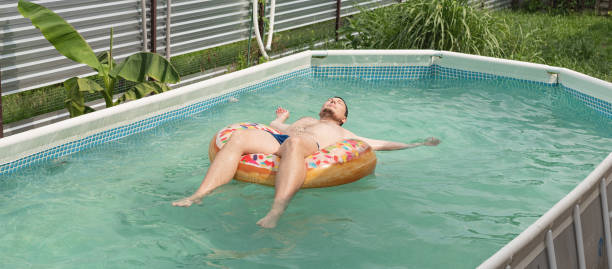 giovane prendere il sole su tubo gonfiabile nuoto in piscina - swimming tube inflatable circle foto e immagini stock