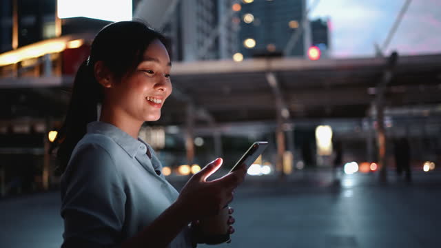 Businesswoman using phone in the City at Night after Work