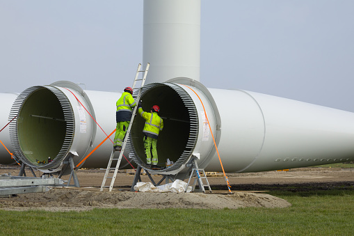 Construction workers preparing the rotor blades of a new wind turbine.