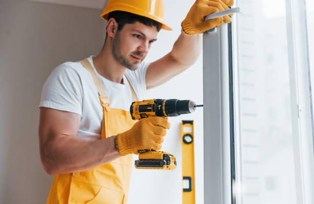 istock Handyman in yellow uniform installs new window by using automatic screwdriver. House renovation conception 1324857706
