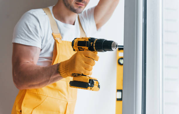 istock Handyman in yellow uniform installs new window by using automatic screwdriver. House renovation conception 1324857717
