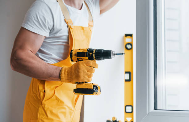 istock Handyman in yellow uniform installs new window by using automatic screwdriver. House renovation conception 1324857725