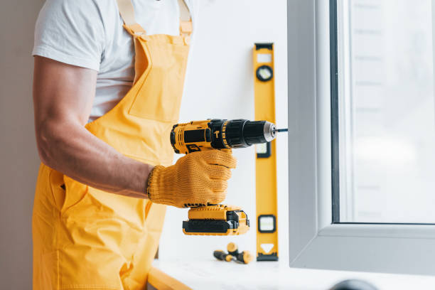 istock Handyman in yellow uniform installs new window by using automatic screwdriver. House renovation conception 1324857745