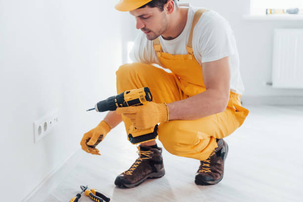 istock Handyman in yellow uniform works with electricity and installing new socket by using automatic screwdriver. House renovation conception 1324858441