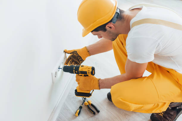 istock Handyman in yellow uniform works with electricity and installing new socket by using automatic screwdriver. House renovation conception 1324858506