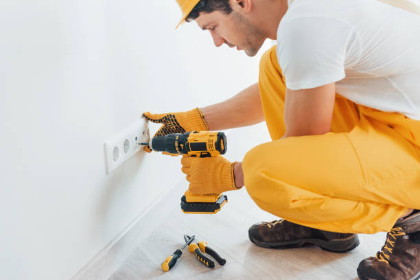 istock Handyman in yellow uniform works with electricity and installing new socket by using automatic screwdriver. House renovation conception 1324858561