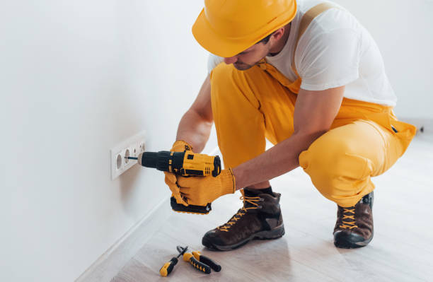 istock Handyman in yellow uniform works with electricity and installing new socket by using automatic screwdriver. House renovation conception 1324858587