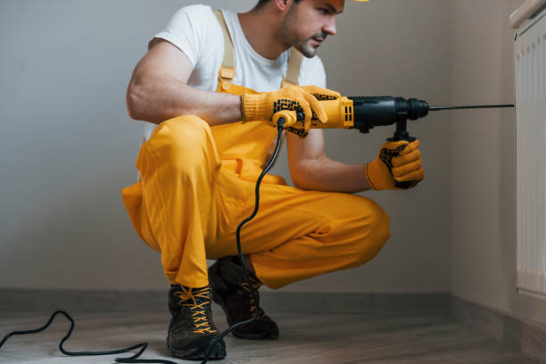 istock Handyman in yellow uniform works with drill indoors. House renovation conception 1324860373
