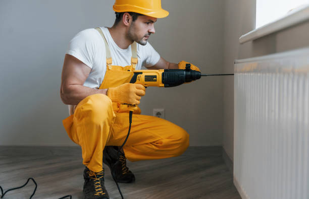 istock Handyman in yellow uniform works with drill indoors. House renovation conception 1324860433