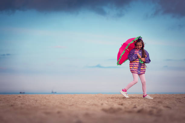 Girl with umbrella standing on the beach