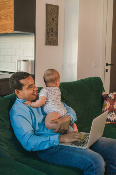 istock Father taking care of son while working on laptop  at home 1324861399