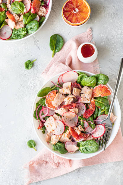 istock Fresh salad with salmon, spinach, radish and red oranges served with orange sauce, light concrete background. Top view. 1324861681