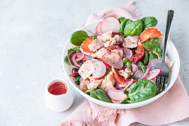 istock Fresh salad with salmon, spinach, radish and red oranges served with orange sauce, light concrete background. 1324861740