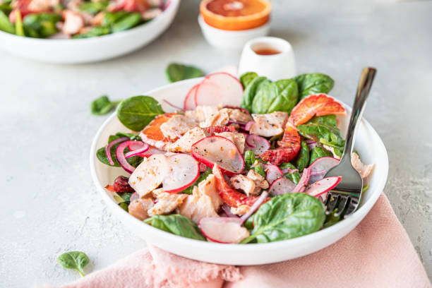 istock Fresh salad with salmon, spinach, radish and red oranges served with orange sauce, light concrete background. 1324861818