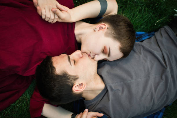 teenager-paar auf gras legen - teenage couple stock-fotos und bilder