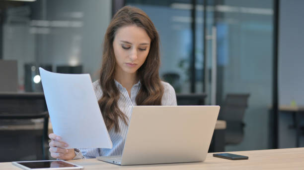istock Young Businesswoman With Laptop having Success on Documents 1324865521