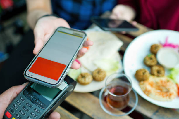 istock Young couple paying with smartphone in a cafe 1324865634