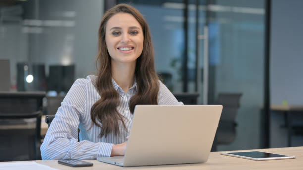 istock Young Businesswoman Smiling at Camera while working on Laptop 1324865682