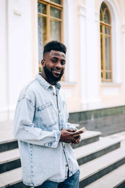 young handsome black businessman using phone outdoors. - surfing wireless vertical outdoors lifestyles imagens e fotografias de stock