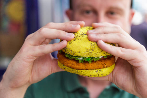 istock Man eating vegan burger in colorful bun 1324869215