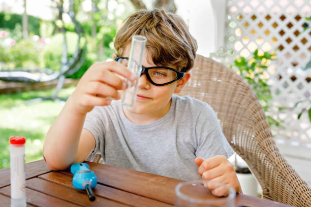 istock Kid boy doing chemical experiment in laboratory at school. Child with protective glasses study using pipette dropping liquid to test tube , caucasian , biochemistry . chemistry class. Summer school. 1324869432
