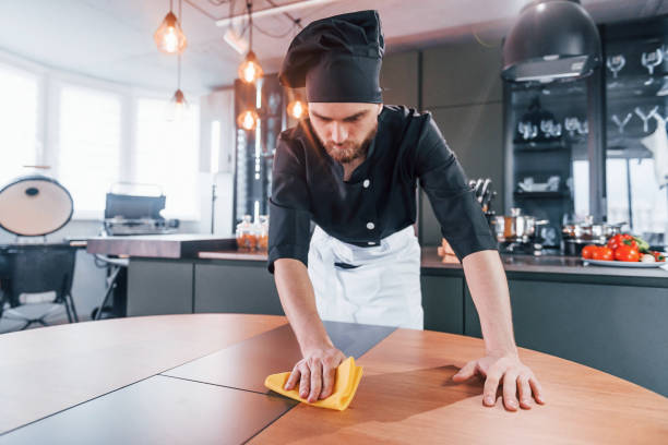 istock Professional young chef cook in uniform cleaning table on the kitchen 1324870680