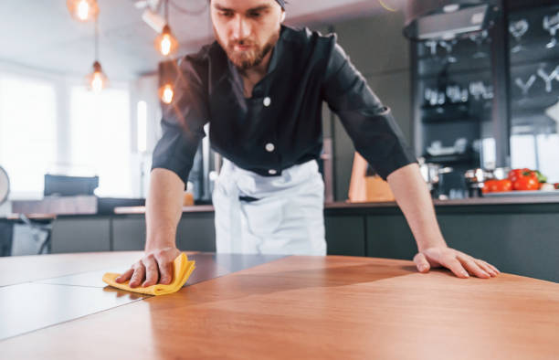 istock Professional young chef cook in uniform cleaning table on the kitchen 1324870720