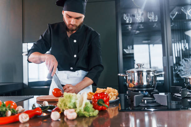 istock Preparing process. Professional young chef cook in uniform working on the kitchen 1324870930