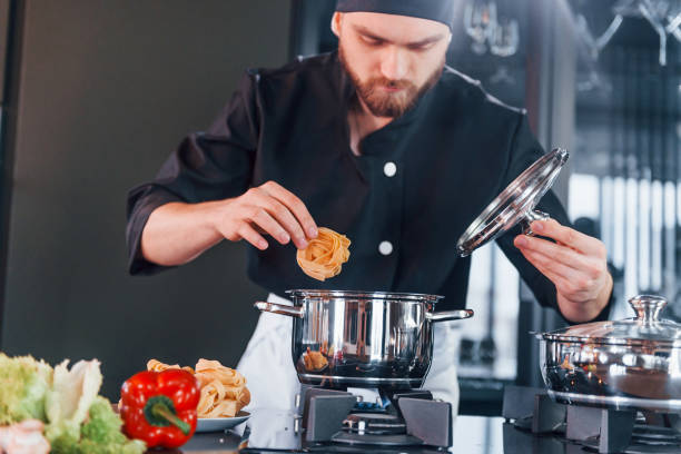 istock Preparing process. Professional young chef cook in uniform working on the kitchen 1324870959
