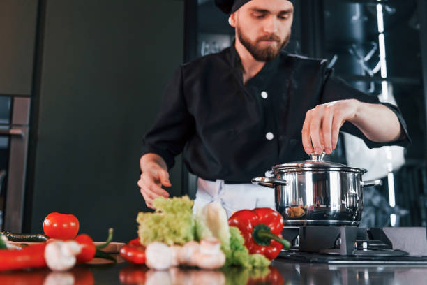 istock Preparing process. Professional young chef cook in uniform working on the kitchen 1324870978