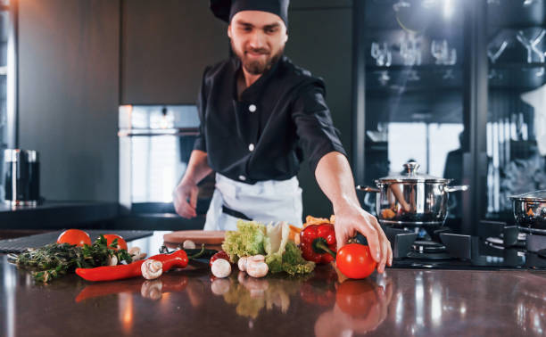 istock Preparing process. Professional young chef cook in uniform working on the kitchen 1324870986