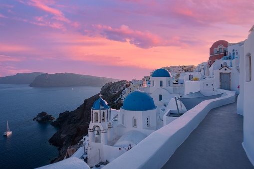 Classical sunset view of the picturesque old town of Oia village on Santorini island, Greece. Included in the picture are the famous blue domes of the Greek Orthodox chapels and small churches.