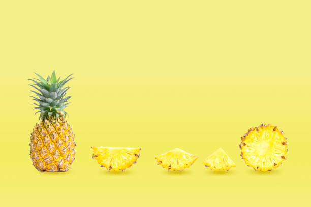 istock group pineapples and sliced isolated on yellow pastel colors background. 1324872139
