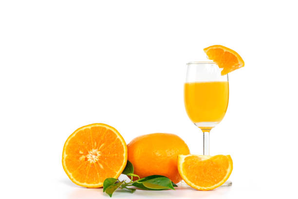 succo d'arancia appena spremuto in un bicchiere, decorato con agrumi e foglie d'arancia - isolated on white orange juice ripe leaf foto e immagini stock