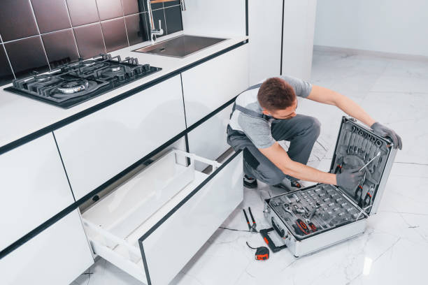 istock Young professional plumber in grey uniform using equipment on the kitchen and preparing for the work 1324872262
