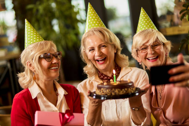 istock Senior ladies taking selfie while celebrating birthday in cafe 1324872418