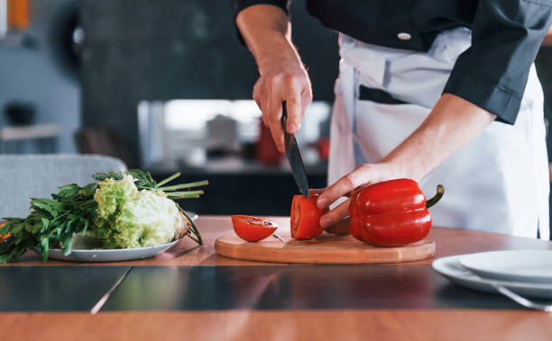 istock Professional young chef cook in uniform making salad on the kitchen 1324872425