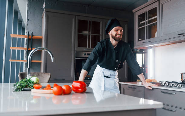 istock Professional young chef cook in uniform making salad on the kitchen 1324872492