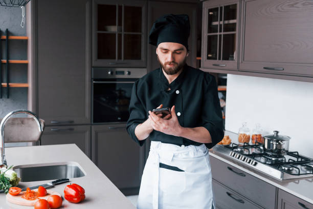 istock Professional young chef cook in uniform standing on the kitchen 1324872499
