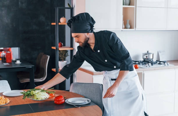 istock Professional young chef cook in uniform making salad on the kitchen 1324872536
