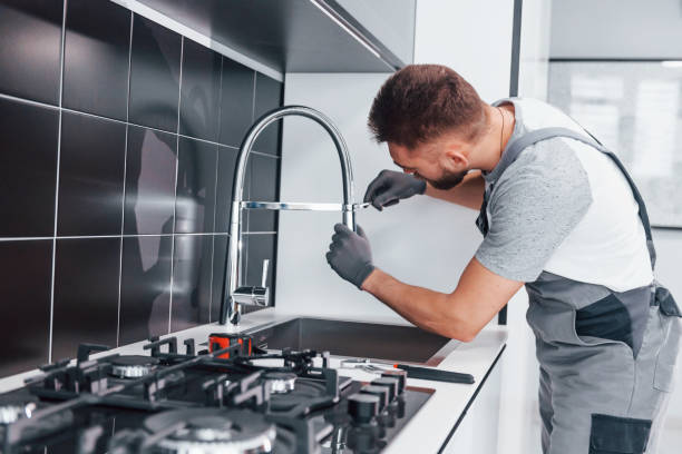 istock Young professional plumber in grey uniform fixing water tap on the kitchen 1324872567