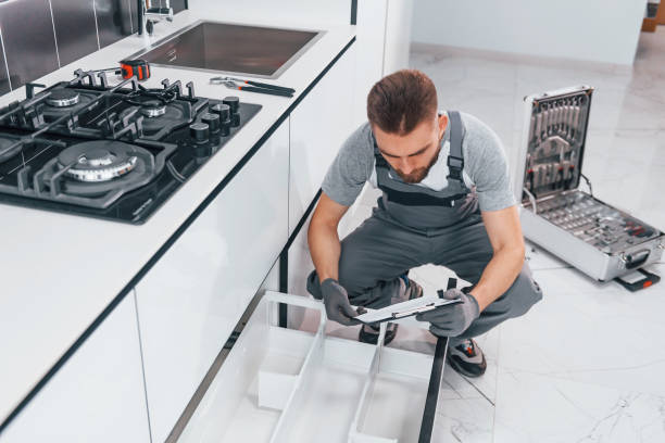 istock Young professional plumber in grey uniform working on the kitchen 1324872585